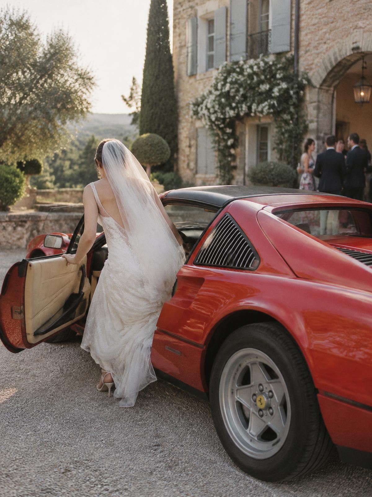 Mariée vue de dos descendant d’une Ferrari 328 GTS dans un domaine près d’Aix-en-Provence